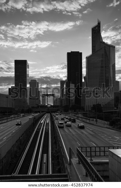 Skyscrapers with glass facade and Grande arch.\
Modern buildings in Paris business district. Concepts of economics,\
financial, future. Copy space. Black and white. Sunset. Evening\
traffic.