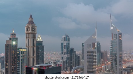 Skyscrapers On Sheikh Zayed Road And DIFC Day To Night Transition Timelapse In Dubai, UAE. Illuminated Towers In Financial Centre Aerial View From Above. Cloudy Sky After Sunset