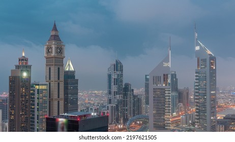 Skyscrapers On Sheikh Zayed Road And DIFC Day To Night Transition Timelapse In Dubai, UAE. Illuminated Towers In Financial Centre Aerial View From Above. Cloudy Sky After Sunset