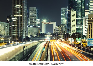 Skyscrapers In Paris Business District La Defense. European Night Cityscape With Dynamic Street Traffic, Car Lights And Glass Facades Of Modern Buildings. Economy, Finances, Transport Concept. Toned