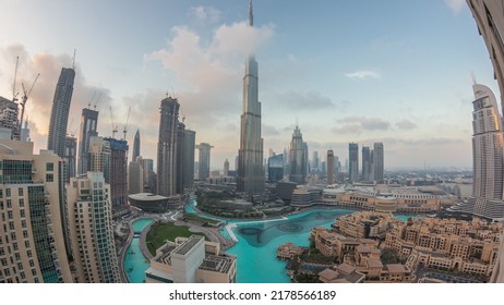 Skyscrapers Rising Above Dubai Downtown Day To Night Transition Timelapse, Mall And Fountain Surrounded By Modern Buildings Aerial Top Panoramic View With Cloudy Sunset Sky