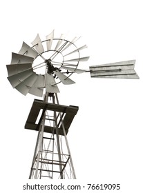 A skyview angle of an old windmill and tower used by early homesteaders to pump water from a well on an isolated white background.