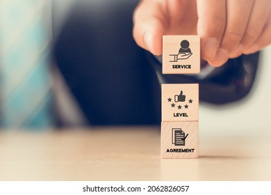SLA - Service Level Agreement acronym, business concept. Service performance tracking to reduce the uncertainty the customer in process. Hand holds  wooden cubes with Service Level Agreement symbols.