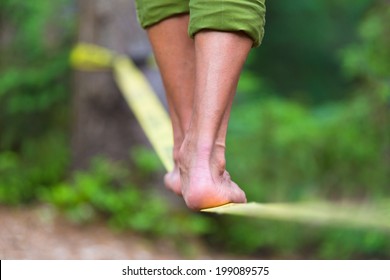 Slacklining is a practice in balance that typically uses nylon or polyester webbing tensioned between two anchor points. - Powered by Shutterstock