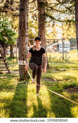 Slacklining is a practice in balance that typically uses nylon or polyester webbing. Girl walking on a slackline in a park during a sunset. Slack line