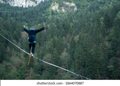 Slacklining upon a deep gorge with trees and mountain as a background (highline)