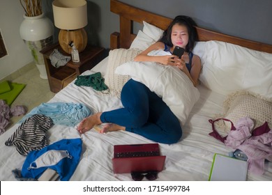 Slackness And Disorganized During Covid-19 Home Lockdown - Young Disorderly And Chaotic Asian Chinese Woman On Bed Using Internet Mobile Phone On Grimy Messy Bedroom In Social Media Addiction