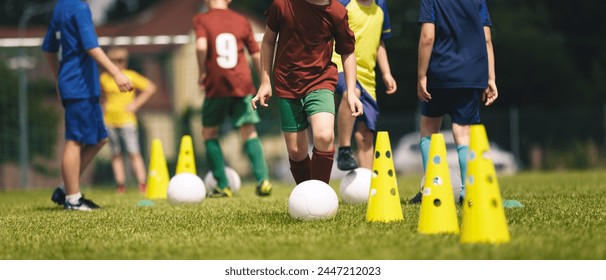 Slalom practice for football players. Youth in sports training. Player kicking ball during a soccer training drill. Summer sports practice camp for school kids - Powered by Shutterstock