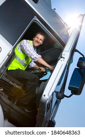 A Slanted Low Angle Vertical Shot Of A Truck Driver In Safety Vest Sitting Inside The Cab Of A Semi-truck And Closing The Door While Smiling At The Camera