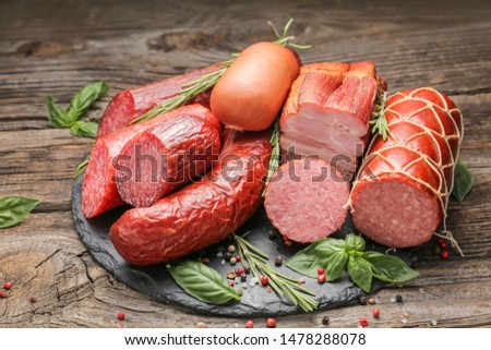 Slate plate with assortment of sausages on wooden table