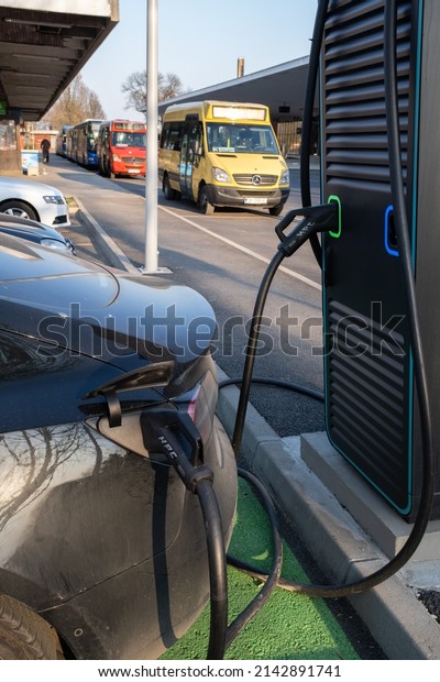 Slavonski\
Brod, Croatia - March 27, 2022: A static shot of a solid black\
Tesla Model 3 dual motor charging at the bus station HPC charging\
station in a sunny spring day. Selective\
focus.