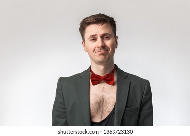 Sleazy, Sexy Man In A Suit And With A Red Bow Tie, Naked, Hairy Chest, Smiling At The Camera, On A Gray Background,