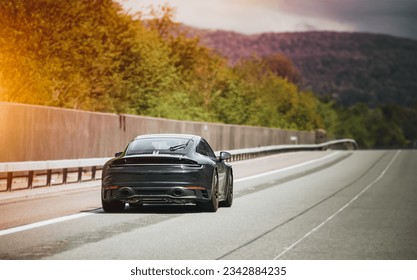 Sleek Black German Roadster. Brand New Luxury Carrera Sports Car on the Highway. Rear view of the 911 GTS sports car.