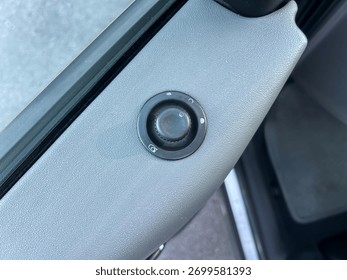 A sleek car window control panel is highlighted, with buttons for window adjustment and lock located on the driver's side. Sunlight reflects on the smooth surface, enhancing its features.