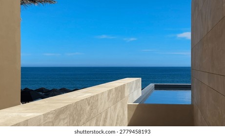 A sleek infinity pool merging with the deep blue ocean, framed by modern stone walls under a bright sky. Luxury coastal architecture