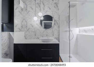 A sleek modern bathroom featuring a stylish vanity with a round mirror, glass shower enclosure, and elegant lighting. The sophisticated design includes marble-patterned walls and contemporary fixtures - Powered by Shutterstock