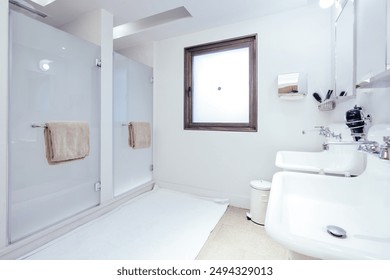 A sleek and modern bathroom interior featuring dual sinks, mirrors, and a well-lit vanity area. The design is clean and minimalist, with a bright and airy feel. Ideal concepts of interior design - Powered by Shutterstock