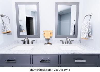 A sleek modern bathroom vanity with a double sink, marble countertop, and gray cabinets, accented with patterned towels and silver faucets - Powered by Shutterstock