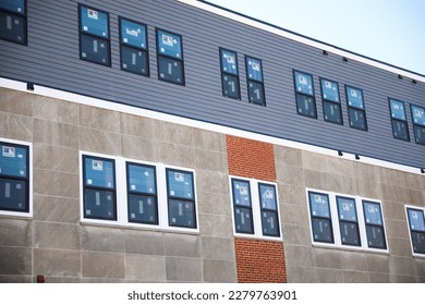 A sleek and modern building exterior with clean lines and large windows that reflect the blue sky. The building features a mix of concrete, steel, and glass, a futuristic and sophisticated look  - Shutterstock ID 2279763901