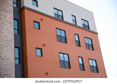 A sleek and modern building exterior with clean lines and large windows that reflect the blue sky. The building features a mix of concrete, steel, and glass, a futuristic and sophisticated look  - Shutterstock ID 2279763917