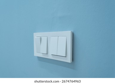 A sleek and modern light switch panel featuring dual switches, set against a calming blue wall. Perfect for contemporary home dcor or interior design inspiration