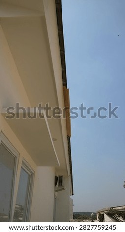 Sleek modern structure with a crisp facade, fitted with windows and an air conditioning unit, all set beneath a vivid blue sky
