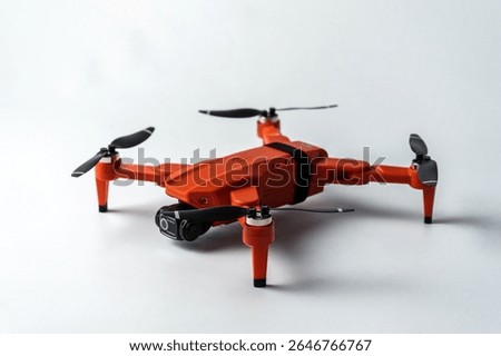 Sleek orange quadcopter drone with camera, isolated on white background for product display
