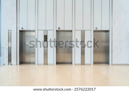 Sleek Three modern elevator with stainless steel doors, white walls, and glossy beige flooring, The professional interior design setting in modern building or office building