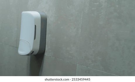 A sleek, wall-mounted soap dispenser in a tiled public restroom. Ideal for hygiene and cleanliness in public spaces, enhancing sanitation standards. - Powered by Shutterstock