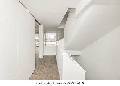 Sleek white interior corridor featuring wood-look tiles, a large sliding door, and a glass balustrade revealing an outdoor swimming pool.