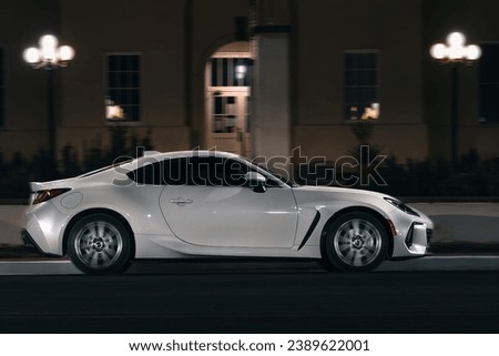 A sleek white sports car parked on the dark street
