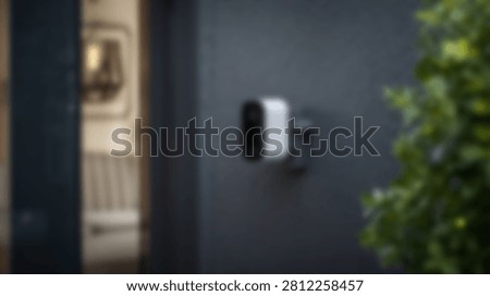 A sleek, white wireless security camera is discreetly mounted on the dark gray exterior wall of a modern home, offering surveillance and peace of mind.