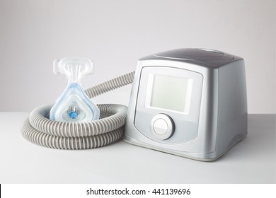 Sleep Apnea CPAP machine with hose and head hear mask, on white table