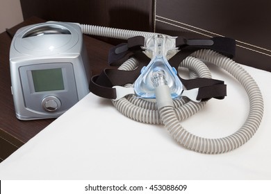 Sleep Apnea CPAP mask, hose, headgear, and machine on bed, selective focus on CPAP mask