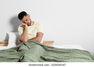 Sleep deprived man sitting on bed at home. Space for text
