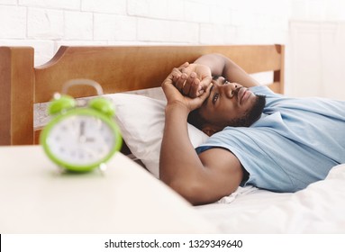 Sleep disorder. Young african-american guy in bed suffering from insomnia, thinking about his problems at night, copy space