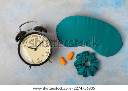 Sleep mask, alarm clock and ear plugs on a marble background. The concept of rest, sleep quality, good night, insomnia, relaxation. Place for text.