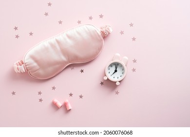 Sleep Mask, Earplugs, Alarm Clock On Pastel Pink Background. Treatments For Insomnia Concept. Flat Lay, Top View