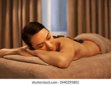Sleep, woman and massage with stone at spa for luxury self care, organic body health and wellness. Towel, table and female person with peace for hot rock therapy, stress relief and spiritual healing - Powered by Shutterstock