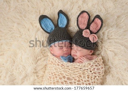 Sleeping 2 month old newborn baby twins wearing bunny costumes. They are swaddled together in a hugging position.