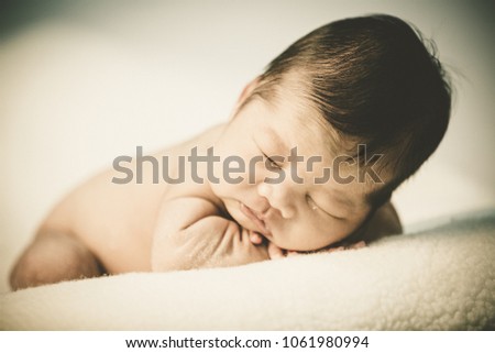 Newborn baby girl sleeping lying on blanket on bed