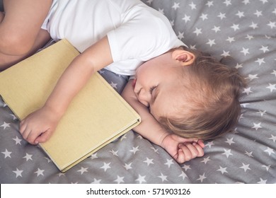 Sleeping Baby Holding A Book In His Hands. Dreaming.