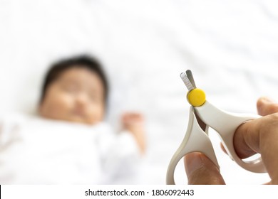 Sleeping Baby And Male Hand Holding A Baby Nail Clipper