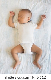 Sleeping Baby On Back On White Bed