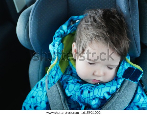 sleeping\
baby rides in a car seat. Happy baby ride in a car. child safety.\
Cute boy sleeping in a car in the child\
seat