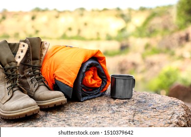 Sleeping bag, cup and boots outdoors on sunny day - Powered by Shutterstock