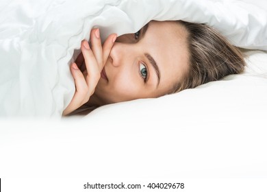Sleeping Beauty looking out of under the blanket. Sweet dreams in the tender soft bed. Beautiful female eye in a whisper tells secrets. Good morning (night) or sweet dreams