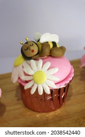 sleeping bee and daisy cupcake on wooden table.