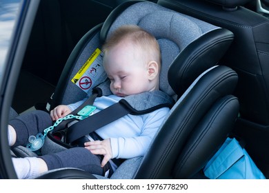 Sleeping Boy, An Baby, Six Months Old, Is Strapped Into A Car Seat In The Passenger Compartment.