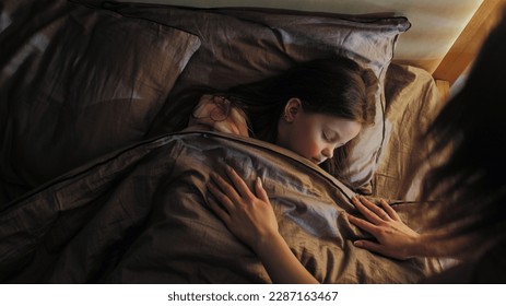 Sleeping child mother care. Night rest. Woman covering peaceful calm daughter with blanket lying in bed at late night in dark home bedroom. - Powered by Shutterstock